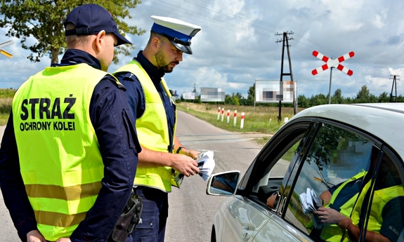 Policjant oraz funkcjonariusz Straży Ochrony Kolei podczas kontroli na przejeździe kolejowym