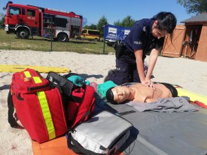 policjantka na plaży wykonuje na fantomie instruktaż z pierwszej pomocy