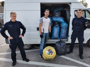 Dwóch umundurowanych policjantów stojących przed busem w towarzystwie mężczyzny