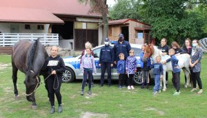policjanci pozują z dziećmi na tle radiowozu