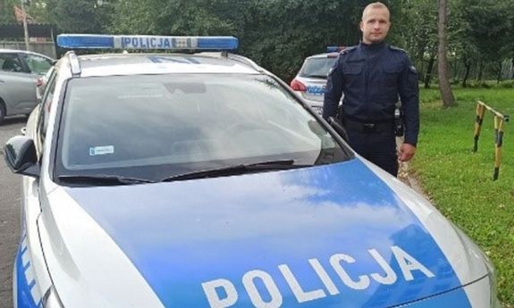 Umundurowany policjant stoi z boku radiowozu