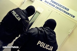 policjanci stoją przed pomieszczeniem dla osób zatrzymanych