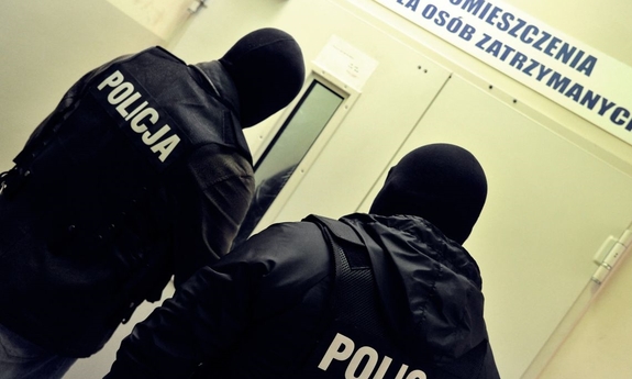 policjanci stoją przed pomieszczeniem dla osób zatrzymanych