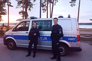 umundurowani policjant i policjantka stoją przy radiowozie