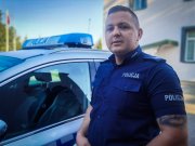 umundurowany policjant stoi przed radiowozem