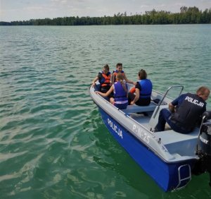 policjamci na łódce z dziećmi ubranymi w kapoki