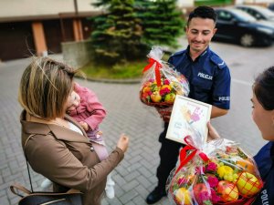 matka z dzieckiem na rękach oraz policjant i policjantka z prezentami