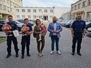 policjant i policjantka z prezentami, matka z dzieckiem na rękach, ojciec dziecka i policjant