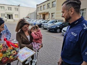 policjantka z prezentem, matka z dzieckiem na rękach i policjant