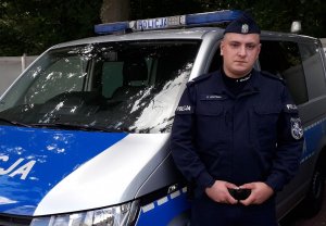 umundurowany policjant stoi przy radiowozie