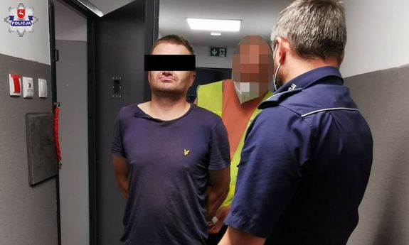 nieumundurowany policjant w maseczce na twarzy zapina kajdanki zatrzymanemu. na pierwszym planie policjant w mundurze stojący twarzą do zatrzymanego