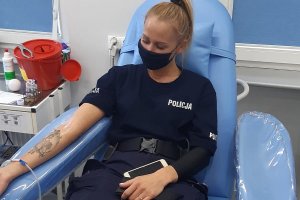 Policjantka, leży na fotelu, ma odsłonięte prawe przedramię i czekana wbicie igły.