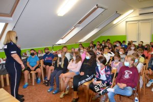 Policjantka rozmawiająca z dziećmi uczestniczącymi w koloniach.