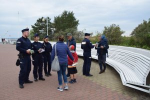 Czwórka policjantów rozdaje odblaski przechodniom.