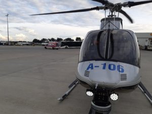 Śmigłowiec Bell na lądowisku, widok na kabinę, przez przednią szybę widać pilota.