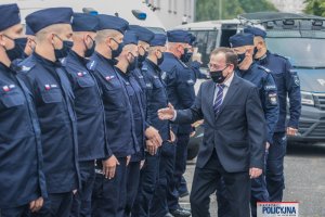 Minister SWiA i Komendant KGP gratulują umundurowanym policjantom stojącym w dwuszeregu, wyciągają dłoń do policjantów