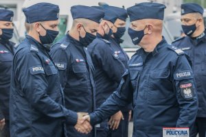 Komendant KGP gratuluje umundurowanym policjantom stojącym w dwuszeregu, ściskając dłoń jednego  z policjantów