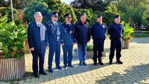 Sześcioosobowa grupa mężczyzn na tle zieleni parku składająca się z umundurowanych polskich i czeskich policjantów oraz dwóch elegancko ubranych mężczyzn