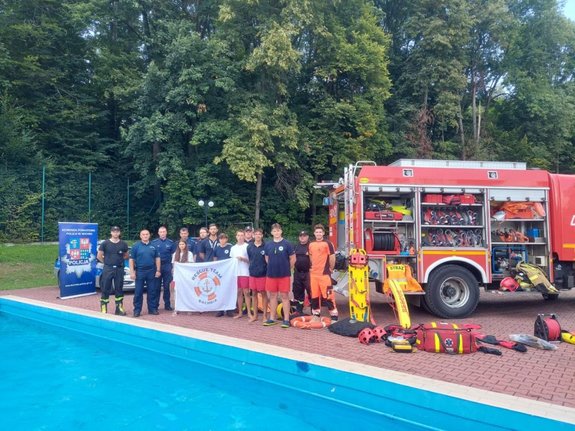 słuzby razezem z młodzieżą pozują dp zdjęcia na tle wozu strażackiego