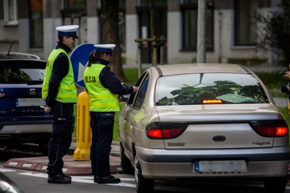 Dwoje policjantów przy kontrolowanym samochodzie osobowym.