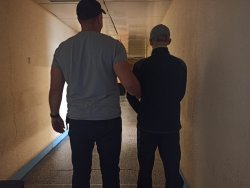 policjant kryminalny stoi w korytarzu z zatrzymanym mężczyzną