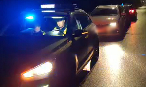 Policyjny radiowóz, za nim zatrzymany pojazd.