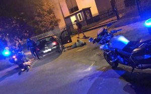 Policyjne motocykle oraz w tle stojący samochód i leżący na ziemi dwaj zatrzymani