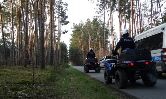 Policyjne quady i radiowozy stojące na leśnej drodze