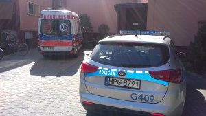 radiowóz policyjny i karetka pogotowia stojące przed budynkiem