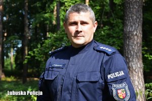 Policjant podczas poszukiwań, rozglądający i poruszający się po lesie wśród drzew