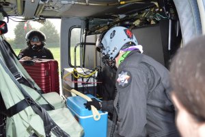 piloci umieszczają  pojemniki w policyjnym Black Hawku