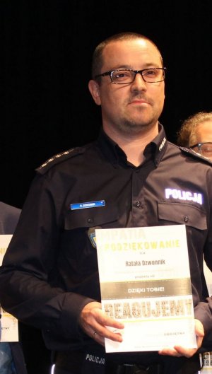 policjant w mundurze trzyma w ręku podziękowanie