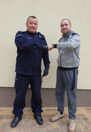 policjant w mundurze ćwiczebnym przybija żółwika ze stojącym obok mężczyzna w dresie