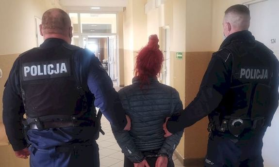 Dwóch policjantów prowadzi zatrzymaną kobietę w kajdankach