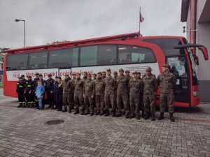 żołnierze, policjanci i strażacy stoją w szeregu przed krwiobusem