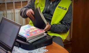 Policjant pracujący przy komputerze oraz przy przeglądaniu teczek