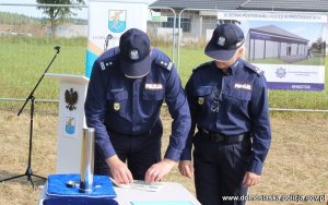 komendant wojewódzki Policji we Wrocławiu nadinspektor Dariusz Wesołowski w mundurze roluje kartkę, obok na stole stoi tuba - kamień węgielny, który zostanie wmurowany pod budowę komisariatu. Obok Komendanta stoi  umundurowana policjantka