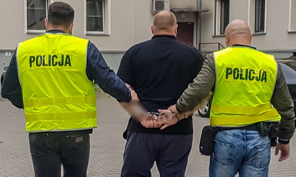 dwaj policjanci prowadzą zatrzymanego mężczyznę