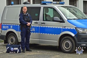 Umundurowany policjant stojący przy radiowozie