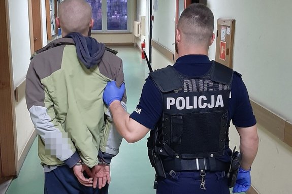 umundurowany policjant prowadzi zatrzymanego