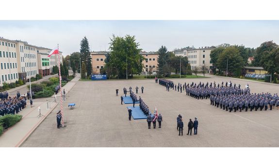 Promocja oficerska absolwentów WSPol. Na placu apelowym z lewej strony kierownictwo WSPol i zaproszeni goście, z prawej strony stojący w szeregach umundurowani policjanci, na środku aktu mianowania poprzez symboliczne uderzenie szablą w ramię dokonują: Komendant Główny Policji gen. insp. Jarosław Szymczyk oraz Pierwszy Zastępca Komendanta Głównego Policji nadinsp. Dariusz Augustyniak.