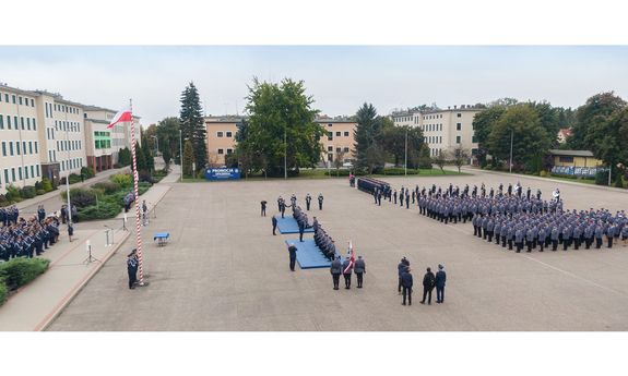 Promocja oficerska absolwentów WSPol. Na placu apelowym z lewej strony kierownictwo WSPol i zaproszeni goście, z prawej strony stojący w szeregach umundurowani policjanci, na środku aktu mianowania poprzez symboliczne uderzenie szablą w ramię dokonują: Komendant Główny Policji gen. insp. Jarosław Szymczyk oraz Pierwszy Zastępca Komendanta Głównego Policji nadinsp. Dariusz Augustyniak.