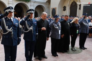 Salutujący policjanci oraz modlący się księża w rzędzie