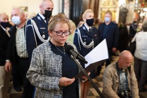 Kobieta, która wygłasza kwestie przez mikrofon w kaplicy. W tle inni ludzie