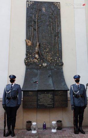 Dwóch policjantów stojących na baczność przy płaskorzeźbie „Gloria Victis&quot;