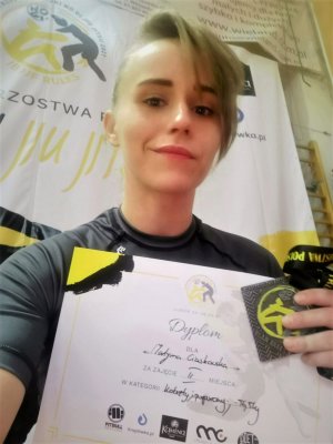 Kobieta pokazująca dyplom oraz medal z zawodów sportowych