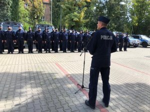 stojący w dwuszeregu umundurowani policjanci i przemawiający, stojący przed nimi za statywem z mikrofonem umundurowany generał - Zastępca Komendanta Głównego Policji nadinsp. Roman Kuster