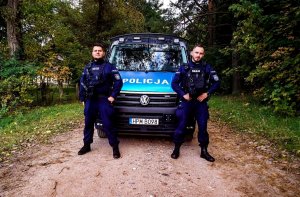 umundurowani policjanci stojący przed radiowozem