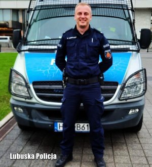 policjant stoi przed radiowozem policyjnym