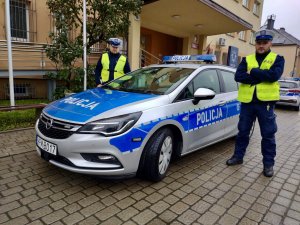 Policjanci stojący przy radiowozie.